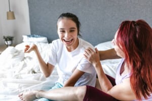 A girl with cerebral palsy laughs while sitting in bed with her mother